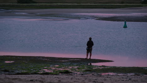 Fisherman-fishing-at-sunset-on-estuary-at-low-tide