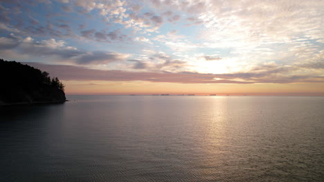 Amanecer-Dorado-Sobre-El-Mar-Con-Un-Cielo-Espectacular,-Sol-Escondido-Detrás-De-Coloridas-Nubes-Esponjosas,-Gdynia-Orlowo---Aéreo