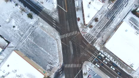 Aerial-cinematic-drone-birds-eye-view-looking-down-downtown-Denver-Colorado-city-buildings-snowing-freezing-cold-winter-day-gray-bird-dramatic-city-landscape-car-traffic-snowy-roads-upward-movement
