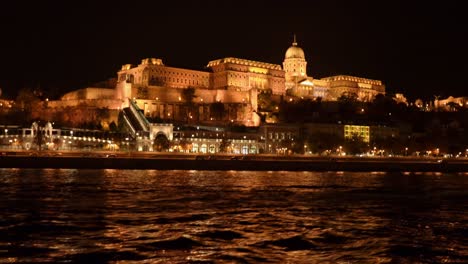 Revealing-shot-of-Buda-Castle-and-Palace-illuminated-with-night-light-at-the-banks-of-river-Danube,-Budapest,-Hungary