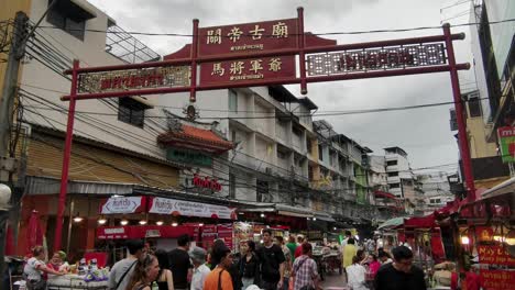 Chinatown-Red-Gate-Entrance-at-Soi-in-Chinatown-with-People-Walking-and-Eating-in-Bangkok,-Thailand