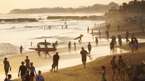 Popular-Canggu-beach-crowded-with-people-enjoying-scenic-sunset-and-surfers,-Bali,-Indonesia