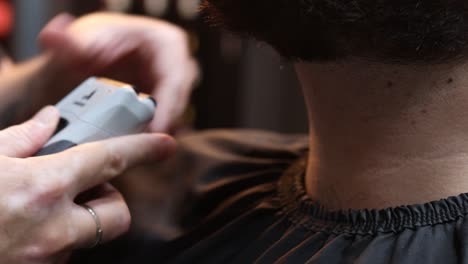 Shot-of-barber-trimming-beard-of-male-client-with-hair-clippers-while-working-in-Barber-shop