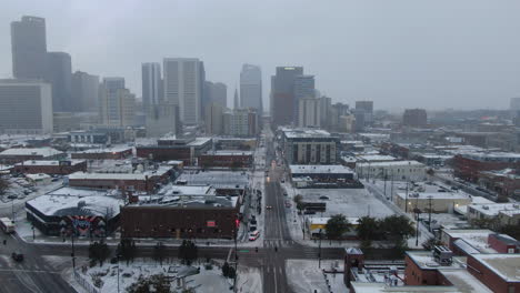 Antena-Cinematográfico-Zumbido-Centro-Denver-Colorado-Ciudad-Edificios-Nevando-Frío-Invierno-Día-Gris-Pájaro-Dramático-Paisaje-De-La-Ciudad-Auto-Tráfico-Rescate-Misión-Jesús-Salva-Letrero-Carretera-Atrás-Pan-Movimiento