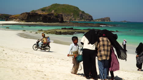 Seller-with-motorbike-ride-on-sandy-beach-of-Indonesia-follow-view