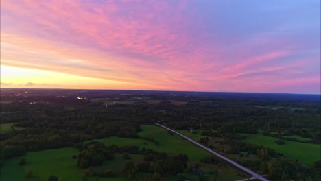 Spektakuläre-Reverse-Zoom-Drohnenaufnahmen-Eines-Herrlich-Farbenfrohen-Sonnenuntergangs-Und-Eines-Schwenks-über-Die-Landschaft-Einer-Ländlichen-Bauerngemeinde
