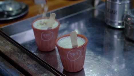 close-up-scene-where-pure-and-organic-A2-milk-is-filled-in-a-clay-cup-with-cashew-nut-masala-powder-being-poured-over-it-which-is-very-tasty