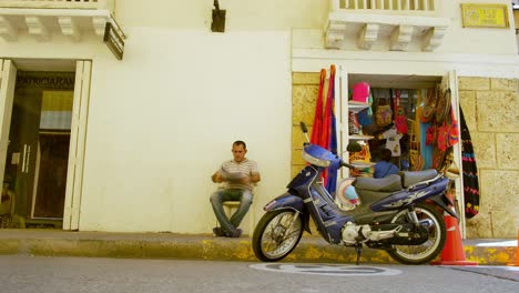 El-Hombre-Se-Sienta-Y-Lee-El-Papel-En-Una-Moto-Azul-Fuera-De-Una-Tienda-En-Cartagena