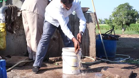 Vista-Frontal-De-Un-Agricultor-Limpiando-Ramas-De-Yuca-Del-Campo-Con-Agua-Para-Eliminar-El-Suelo