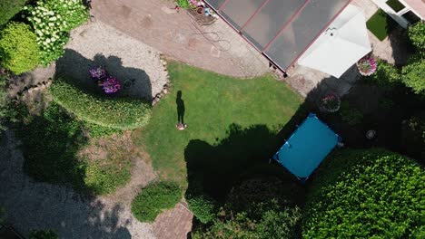 A-young-little-girl-doing-a-handstand-exercise-in-the-backyard-of-her-home,-Top-down-aerial-view