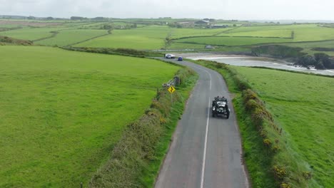 drone-view-of-vintage-car-climbing-the-hill-out-of-Kilmurrin-Cove-Copper-Coast-Waterford-Ireland