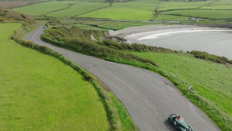 Classic-cars-climbing-the-hill-out-of-Kilmurrin-Cove-Copper-Coast-Waterford-Ireland-on-a-blustery-summer-morning