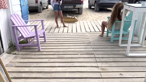 two-friends-models-and-skaters-doing-a-photo-session-and-taking-photos-with-camera-on-the-wooden-platform-near-the-beach