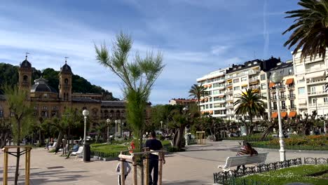 Foto-Panorámica-Del-Parque-Con-Gente-Cerca-De-La-Playa-En-San-Sebastián-Durante-El-Día-Soleado---Ayuntamiento-De-San-Sebastián-En-Segundo-Plano