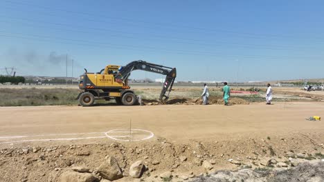 Excavadora-Aérea-Excavando-Trincheras-Junto-A-Un-Camino-De-Tierra-De-Grava-En-Pakistán