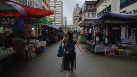Asian-woman-walking-fast-along-street-market-on-bright-day