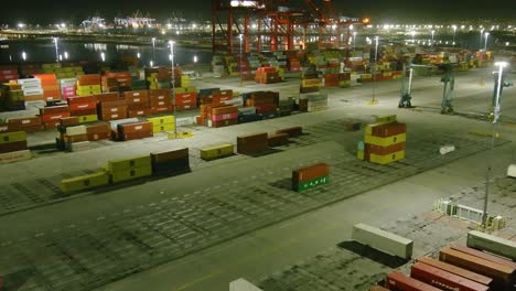 Aerial-flyby-over-shipping-containers-at-Long-Beach-shipping-port-|-Night-time-|-Ocean-in-background