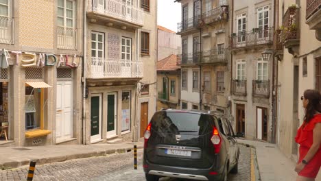 Turista-En-La-Acera-Con-Tráfico-Rodado-En-El-Casco-Antiguo,-Distrito-De-Ribeira-En-Porto,-Portugal