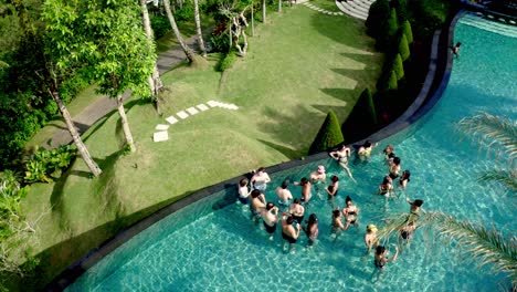 Aerial-established-shot-of-Young-people-swimming-in-pool-while-on-holiday
