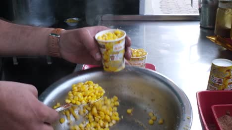 Close-up-scene-of-a-man-filling-a-cup-with-freshly-sweet-corn-ready-to-be-eaten