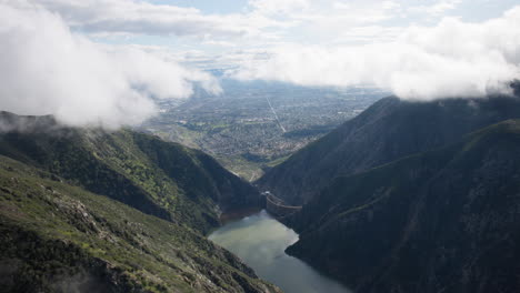 Morning-view-through-the-cloudy-mountains,-lake-and-dam-on-an-helicopter-close-to-the-valley-of-Los-Angeles