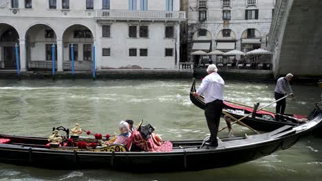 Gondola's-Passing-Each-On-The-Grand-Canal-Beside-Rialto-Bridge-In-Venice-On-Sunny-Day