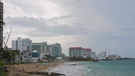 Tourists-enjoy-the-beach-in-the-hotel-area-of-Condado,-San-Juan,-Puerto-Rico-during-a-cloudy-and-windy-day