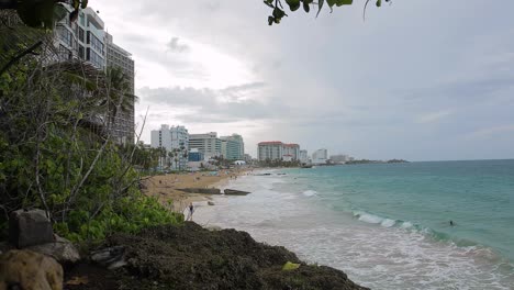 Los-Turistas-Disfrutan-De-La-Playa-En-La-Zona-Hotelera-De-Condado,-San-Juan,-Puerto-Rico-Durante-Un-Día-Nublado-Y-Ventoso