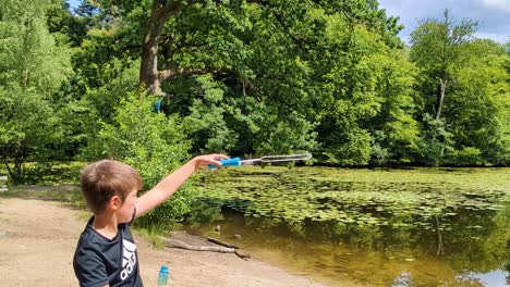 4k-60fps-Junge-Bläst-Seifenblasen-In-Einem-Wald-An-Einem-Wunderschönen-Waldsee