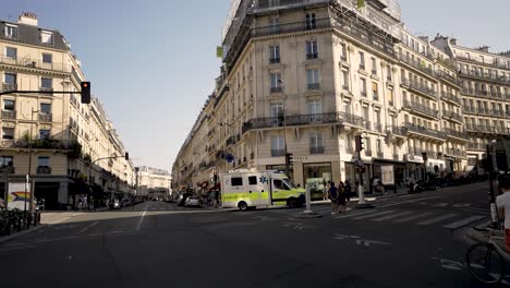 Ambulance-turning-along-the-streets-of-the-city-with-people-watching,-Moving-away-shot
