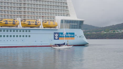 Sailboat-Sailing-Beside-Royal-Caribbean-International-Quantum-Of-The-Seas-Luxury-Cruise-Ship,-4K-Slow-Motion