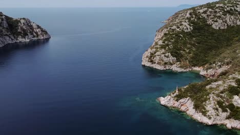 Aerial-drone-flight-over-blue-ocean-with-rocky-coastline-during-sunny-day-in-Greece