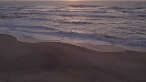Reveal-shot-of-Praia-da-Areeira-Portugal-during-sunset-with-big-waves,-aerial
