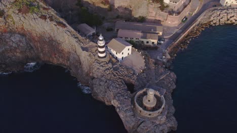 Top-down-of-lighthouse-at-Port-de-Sóller-Mallorca-during-sunset,-aerial