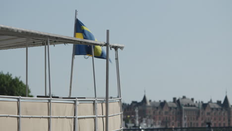 Bandera-Sueca-Se-Mueve-En-El-Viento-En-Dirección-De-Barco-En-Estocolmo,-Vista-Cercana