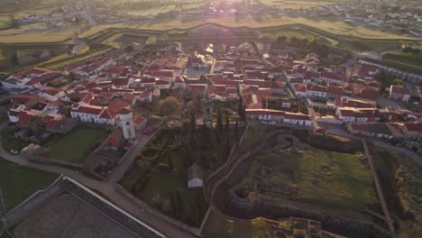 Tilt-up-shot-of-Touristic-town-Almeida-Portugal-with-sun-in-lens-at-sunrise,-aerial