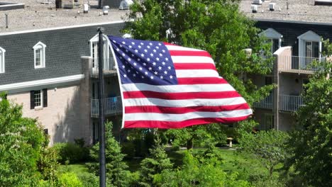 Panoramic-view-of-an-apartment-complex-with-the-focal-point-of-the-American-flag-flowing-gently-in-the-breeze
