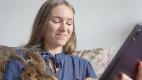 Camera-footage,-girl-relaxing-on-sofa,-using-smart-pen-to-write-on-tablet