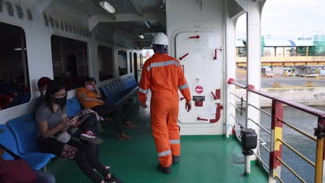 Asian-Man-working-on-ship-walks-past-passengers-Ferry-Workers