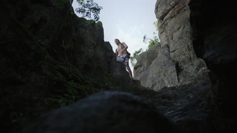 man-on-rocky-hiking-trail,-sporty-guy-hikes-jumps,-mountain,-walks-a-mountain-trail-bare-chest,-mountaineer-gear,-climbing-outdoors,-sunny-summer-weather-in-Austria,-Durnstein,-Europe