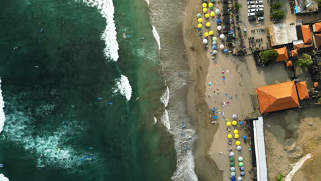 Top-down-aerial-view-of-crowded-Batu-Bolong-Beach,-Canggu,-Indonesia