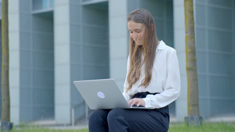 Young-businesswoman-in-elegant-clothes,-sitting-outside-and-working-at-laptop