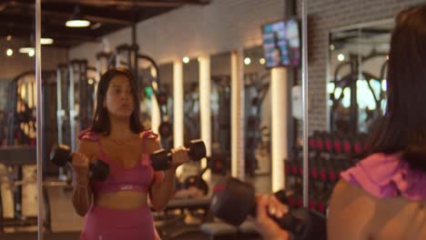 A-young-woman-at-the-gym-in-sports-wear-lifting-dumbells-at-the-gym