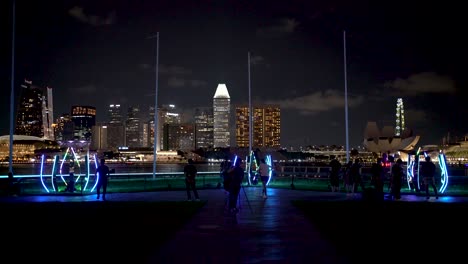Grupo-De-Personas-Tomando-Fotos-Y-Videos-De-Las-Instalaciones-De-Iluminación-En-El-Festival-Anual-I-Light-Celebrado-En-Marina-Bay,-Singapur