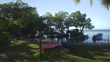 Orilla-De-La-Playa-En-Punta-Gorda,-Roatán,-Honduras-Con-Varios-Botes-Pequeños-Abandonados,-Kayak-Y-Panga-De-Pesca