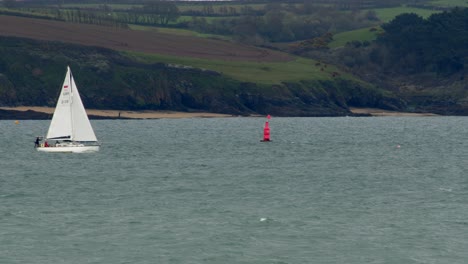 Sailboat,-passing-a-marker-buoy-with-St-Mawes-in-the-background