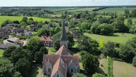 An-aerial-push-in-shot-over-Ickham-village-and-St-John-the-Evangelist-church,-with-fields-stretching-out-in-the-background