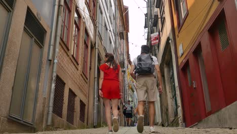 Low-angle-shot-in-the-old-and-historic-center-of-a-couple-walking-among-tourists-in-Porto,-Portugal