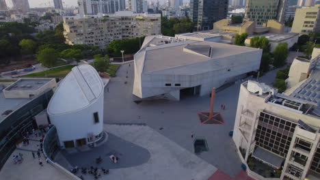The-modern-architecture-of-the-Tel-Aviv-Museum-at-sunset-with-the-city's-skyline---Pull-back-in-shot