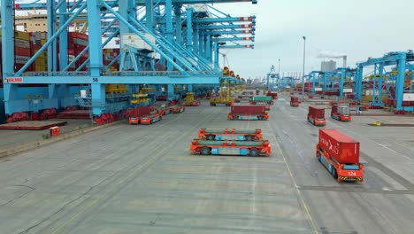 Drone-panning-shot-of-agv's-moving-around-while-cranes-discharge-containers-from-a-vessel